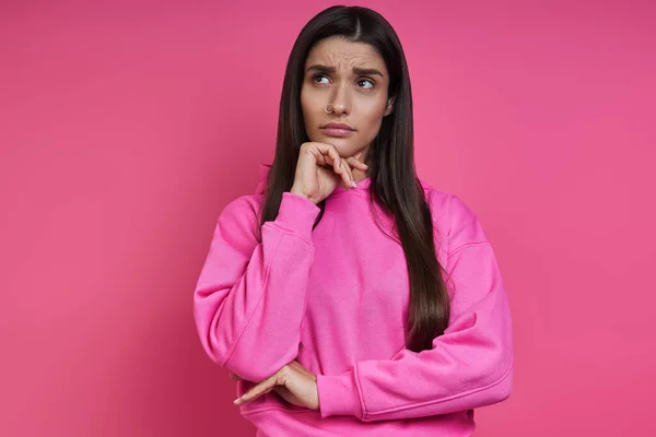 Thoughtful Young Woman Holding Hand Chin While Standing Pink Background — Foto Stock