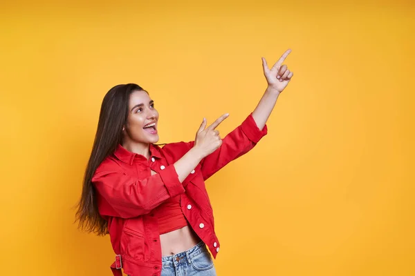 Excited Young Woman Pointing Away While Standing Yellow Background — Stockfoto