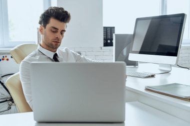 Handsome young man using computer while sitting at his working place in office
