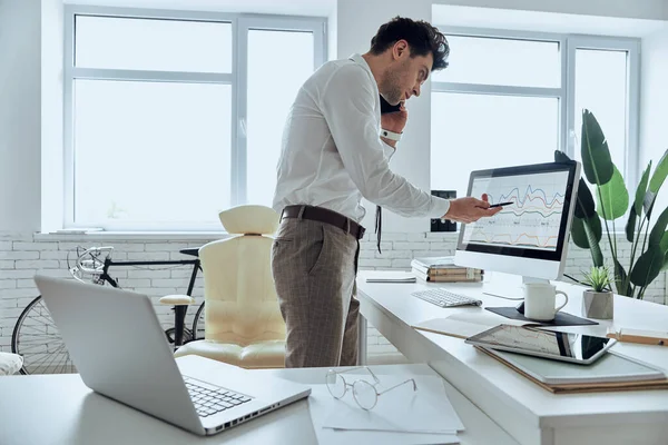 Confident Man Looking Computer Monitor Pointing While Talking Phone Office — Stock fotografie