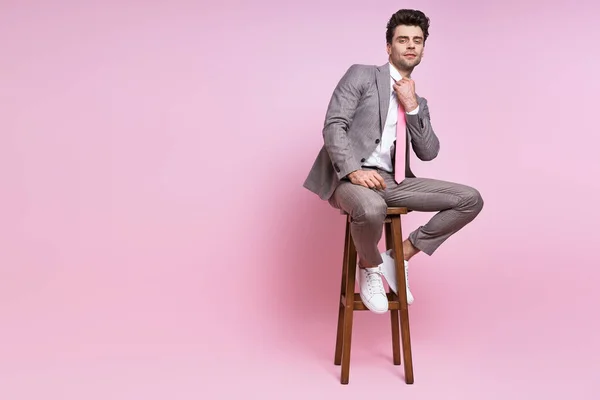 Confident Man Full Suit Adjusting His Necktie While Sitting Chair — Foto de Stock