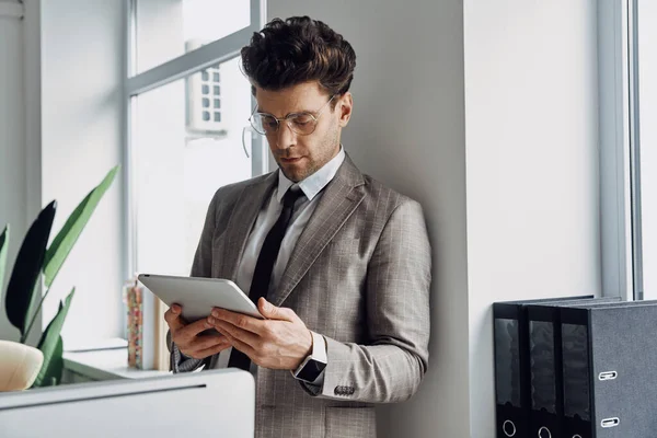 Confident Young Man Using Digital Tablet While Standing Window Office — ストック写真