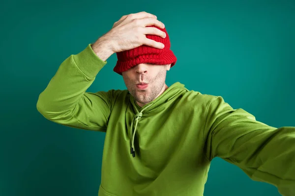 Playful Young Man Making Selfie Pulling Hat Face While Standing — Stock Photo, Image