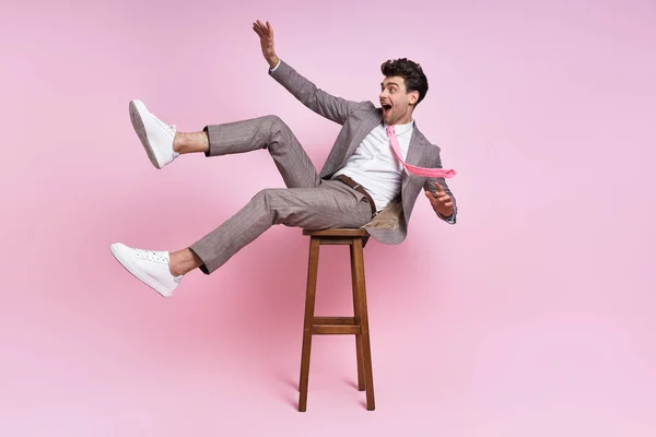 Щасливий Молодий Чоловік Повному Костюмі Розважається Сидячи Стільці Рожевому Фоні — стокове фото