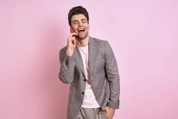 Красивий Чоловік Костюмі Говорить Мобільному Телефоні Посміхається Стоячи Рожевому Фоні — стокове фото