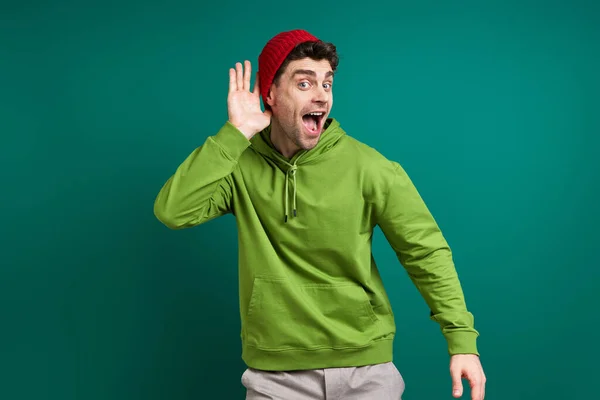 Handsome Young Man Holding Hand Ear While Standing Green Background — Photo