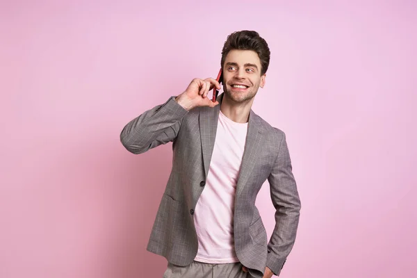 Щасливий Молодий Чоловік Костюмі Говорить Мобільному Телефоні Стоячи Рожевому Фоні — стокове фото