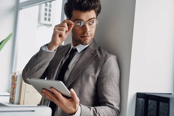 Confident Man Holding Digital Tablet Adjusting Eyeglasses While Standing Office — ストック写真
