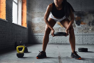 Close-up of confident woman lifting weights while exercising in gym