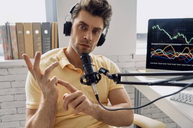 Confident man in headphones using microphone and gesturing while recording his business podcast