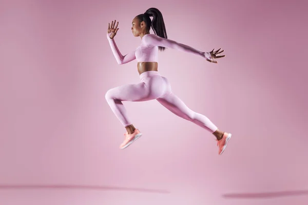 Confident Young Woman Sports Clothing Jumping Pink Background — Stockfoto