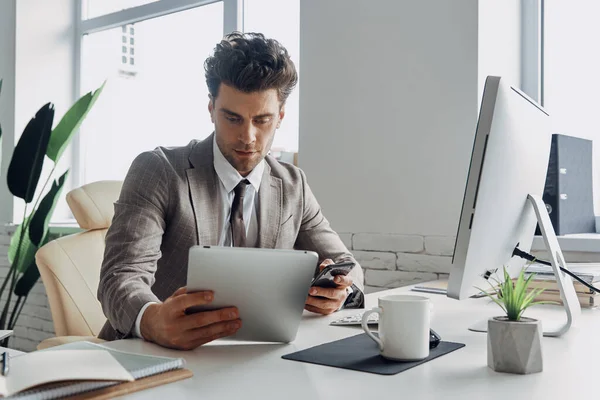 Handsome Young Man Using Digital Tablet Holding Smart Phone While — Stok fotoğraf