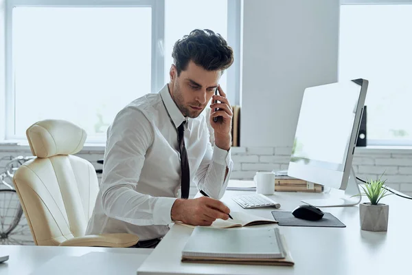 Confident Man Shirt Tie Making Notes Talking Phone While Sitting – stockfoto