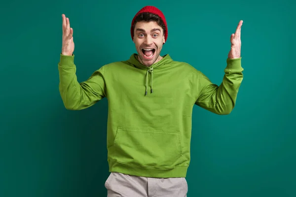 Возбужденный Молодой Человек Жестикулирует Стоя Зеленом Фоне — стоковое фото