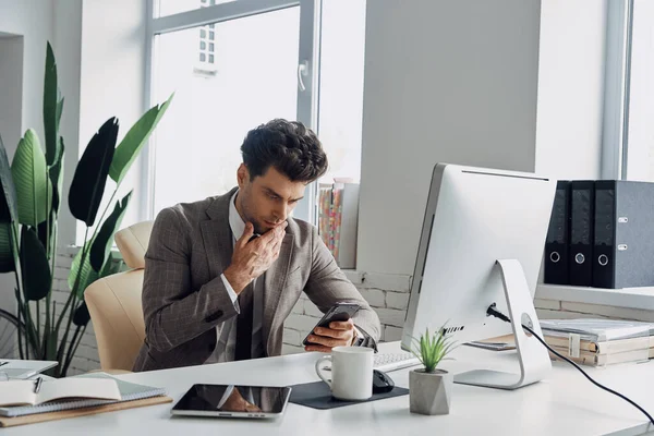Thoughtful Young Man Using Smart Phone While Sitting His Working — Foto de Stock