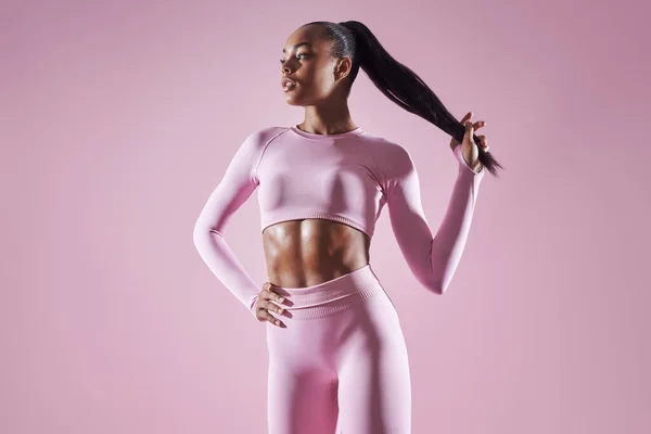 Confident African Woman Sports Clothing Adjusting Her Hair Pink Background —  Fotos de Stock