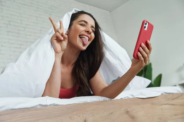 Playful Young Woman Covering Blanket While Making Selfie Smart Phone — Stock Fotó