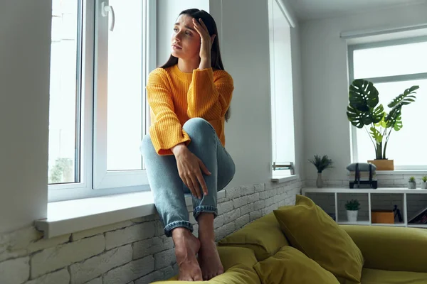 Depressed Woman Touching Head Looking Window While Sitting Window Sill — Stok fotoğraf