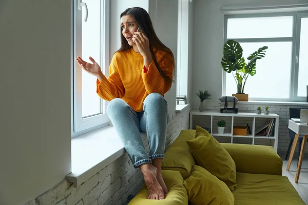 Worried Woman Talking Mobile Phone Gesturing While Sitting Window Sill — 图库照片