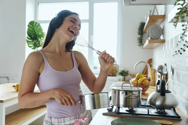 Playful Young Woman Headphones Using Whisk Microphone While Cooking Kitchen — Stock Fotó