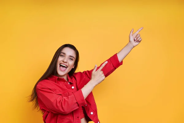 Happy Young Woman Pointing Away While Standing Yellow Background — Stockfoto