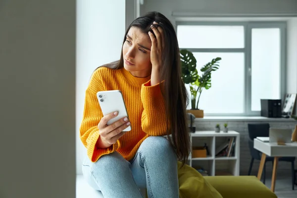 Depressed Woman Holding Smart Phone Touching Head While Sitting Window — Fotografia de Stock