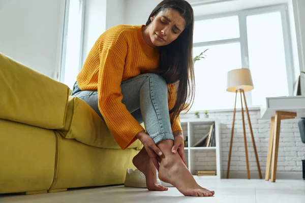 Close Young Depressed Woman Touching Her Foot While Sitting Couch — Foto de Stock