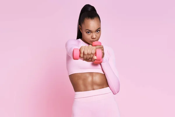 Concentrated Young Woman Exercising Dumbbells While Standing Pink Background — Foto de Stock