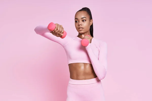 Beautiful Young African Woman Exercising Dumbbells While Standing Pink Background — Stock fotografie