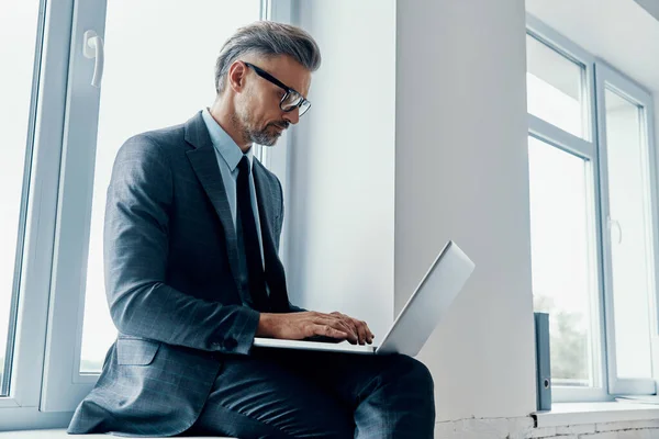 Concentrated Mature Man Formalwear Using Laptop While Sitting Window Sill — ストック写真