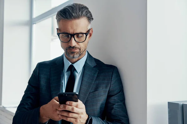 Confident Mature Man Formalwear Using Smart Phone While Standing Window — 图库照片