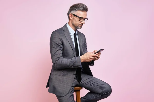 Αυτοπεποίθηση Ώριμος Άνθρωπος Formalwear Χρησιμοποιώντας Έξυπνο Τηλέφωνο Ενώ Κάθεται Ροζ — Φωτογραφία Αρχείου