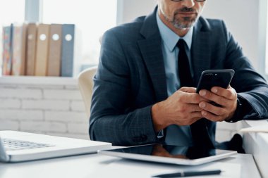Close-up of unrecognizable mature man in formalwear using laptop while sitting in the office