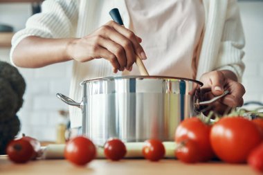 Mutfakta yemek hazırlarken tavada bir şeyler karıştıran tanınmayan bir kadının yakın çekimi.