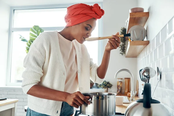 Mulher Africana Bonita Degustação Colher Enquanto Prepara Comida Cozinha — Fotografia de Stock