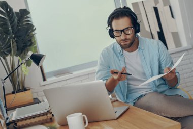 Ofisteki internet konferansı sırasında iş hakkında konuşan kulaklıklı yakışıklı genç adam.