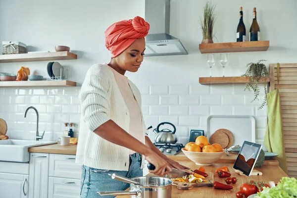 Geleneksel Başlıklı Kendine Güvenen Genç Afrikalı Kadın Mutfakta Sebze Kesiyor — Stok fotoğraf