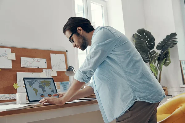 Selbstbewusster Junger Mann Benutzt Laptop Während Der Nähe Seines Arbeitsplatzes — Stockfoto