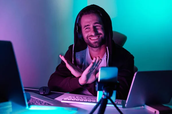 Handsome young man looking at the computer monitor and gesturing against colorful background