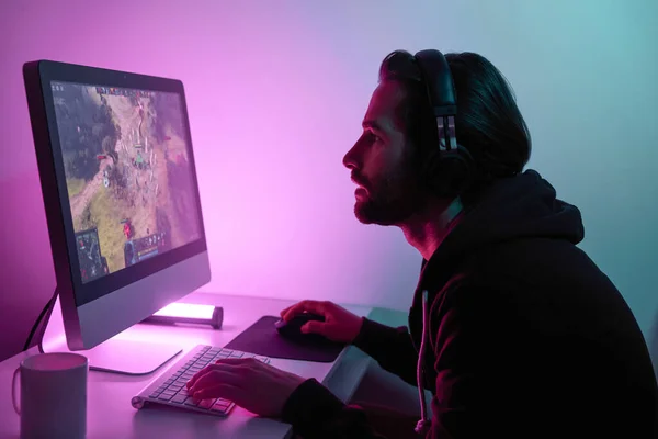 Silhouette of man looking at the computer monitor while playing game against colorful background