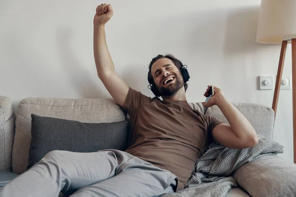 Happy Young Man Headphone Holding Smart Phone Gesturing While Relaxing — Stok Foto