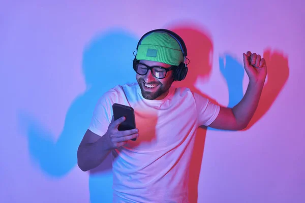 Hombre Guapo Auriculares Sonriendo Haciendo Gestos Mientras Mira Teléfono Inteligente —  Fotos de Stock