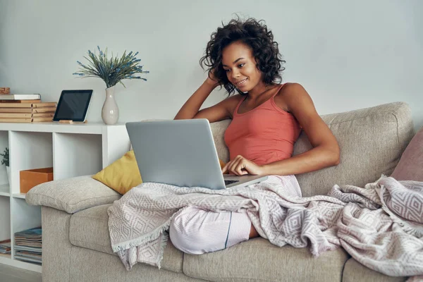 Mulher Africana Bonita Usando Laptop Enquanto Sentado Sofá Casa — Fotografia de Stock