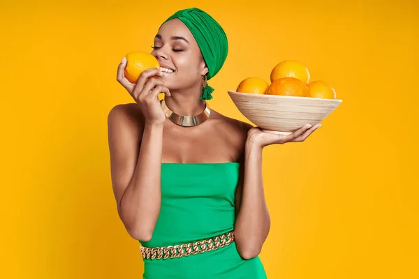 Beautiful African Woman Traditional Headwear Smelling Oranges Smiling Yellow Background — Stock Photo, Image