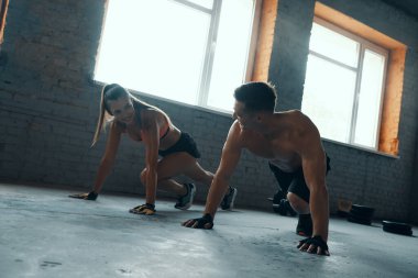 Genç ve zinde bir çift birbirlerine bakıyor ve birlikte spor yaparken gülümsüyor.
