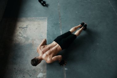 Genç kaslı bir adamın spor salonunda şınav çekmesi.