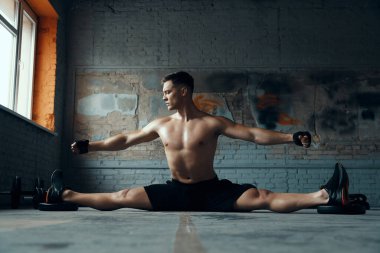 Kendine güveni olan genç adam spor salonunda egzersiz yaparken kollarını açık tutuyor.