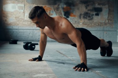 Confident young man doing push-up exercises in gym