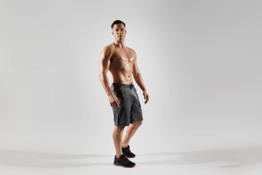 Mükemmel gövdeli yakışıklı adam beyaz arka planda duruyor.