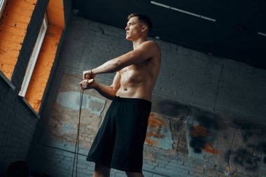 Spor salonunda egzersiz yaparken ip atlayan kendine güvenen bir genç.